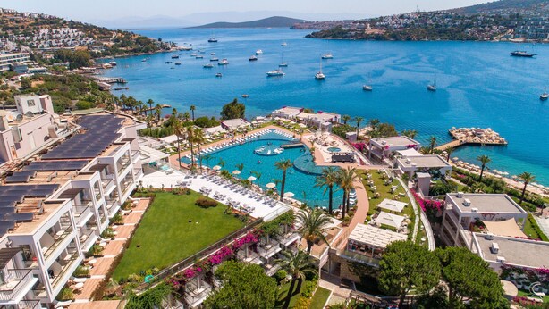 Un complexe hôtelier doté d’une grande piscine, de plusieurs terrasses et offrant une vue sur la mer et les bateaux.