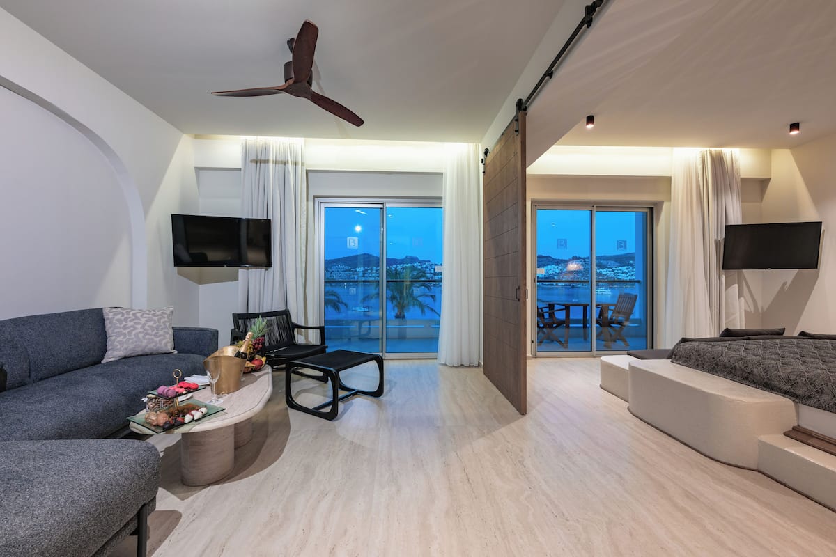Een moderne woonkamer met een bank, salontafel en televisie. Er is een balkon met uitzicht op de stad.