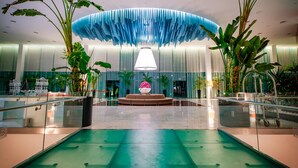 Un hall d’entrée spacieux agrémenté d’une fontaine centrale, de grands pots de plantes et d’un design moderne au plafond.