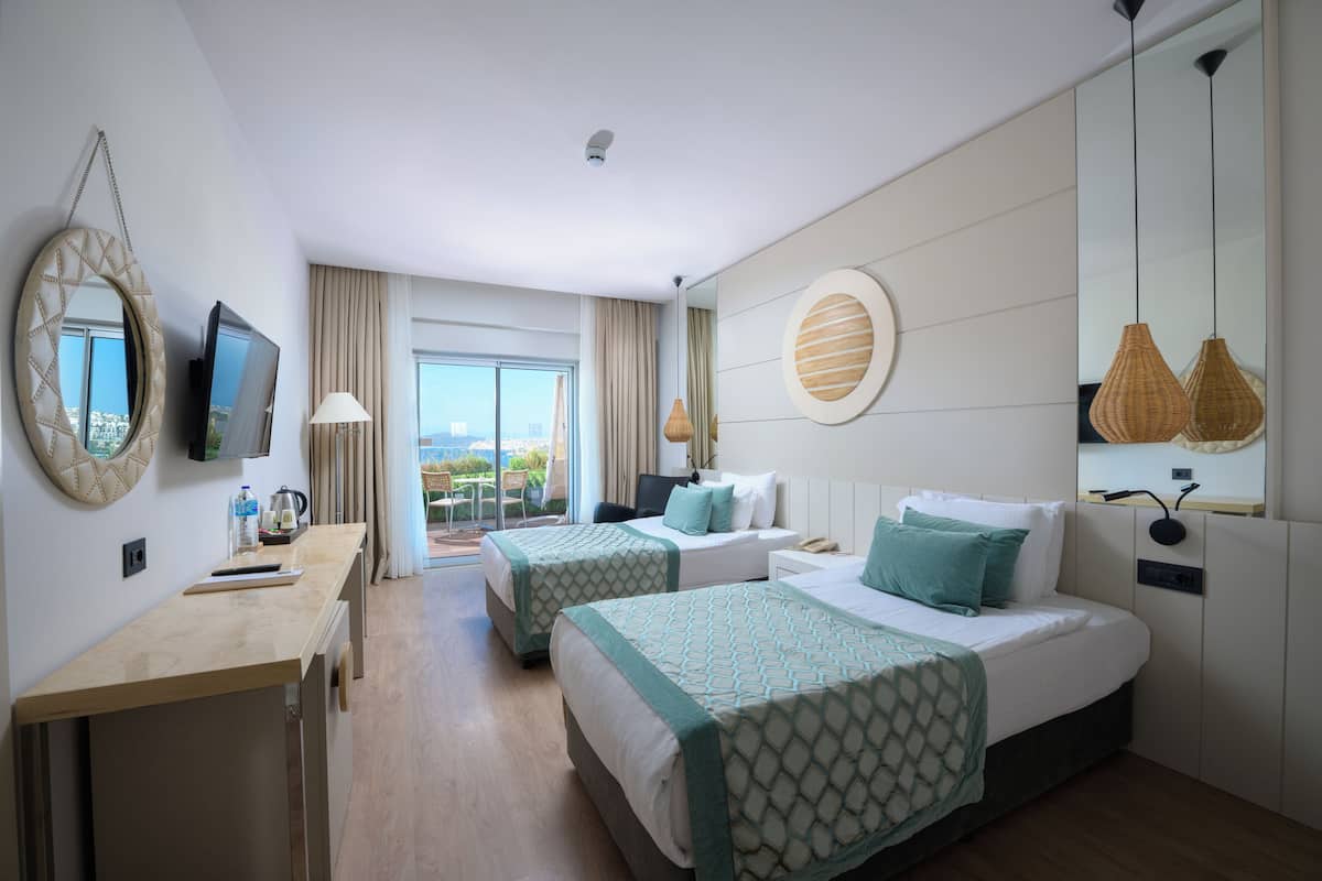 Een hotelkamer met twee bedden, een bureau, een televisie en een balkon met uitzicht.