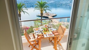 Un balcon avec une table préparée pour le petit-déjeuner, donnant sur une étendue d’eau et un quai.