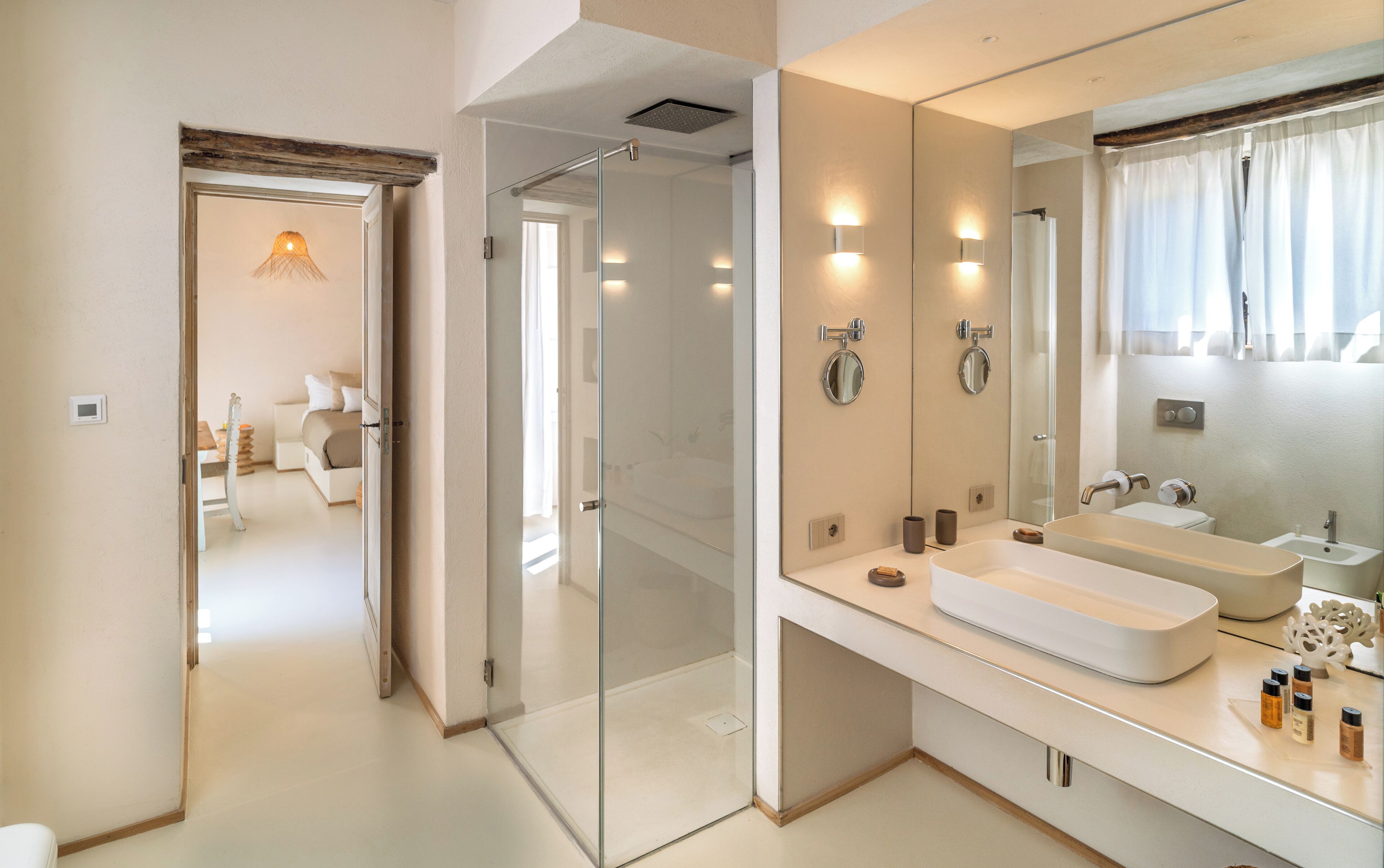 A modern bathroom with a glass shower enclosure, a large mirror, and a white sink.