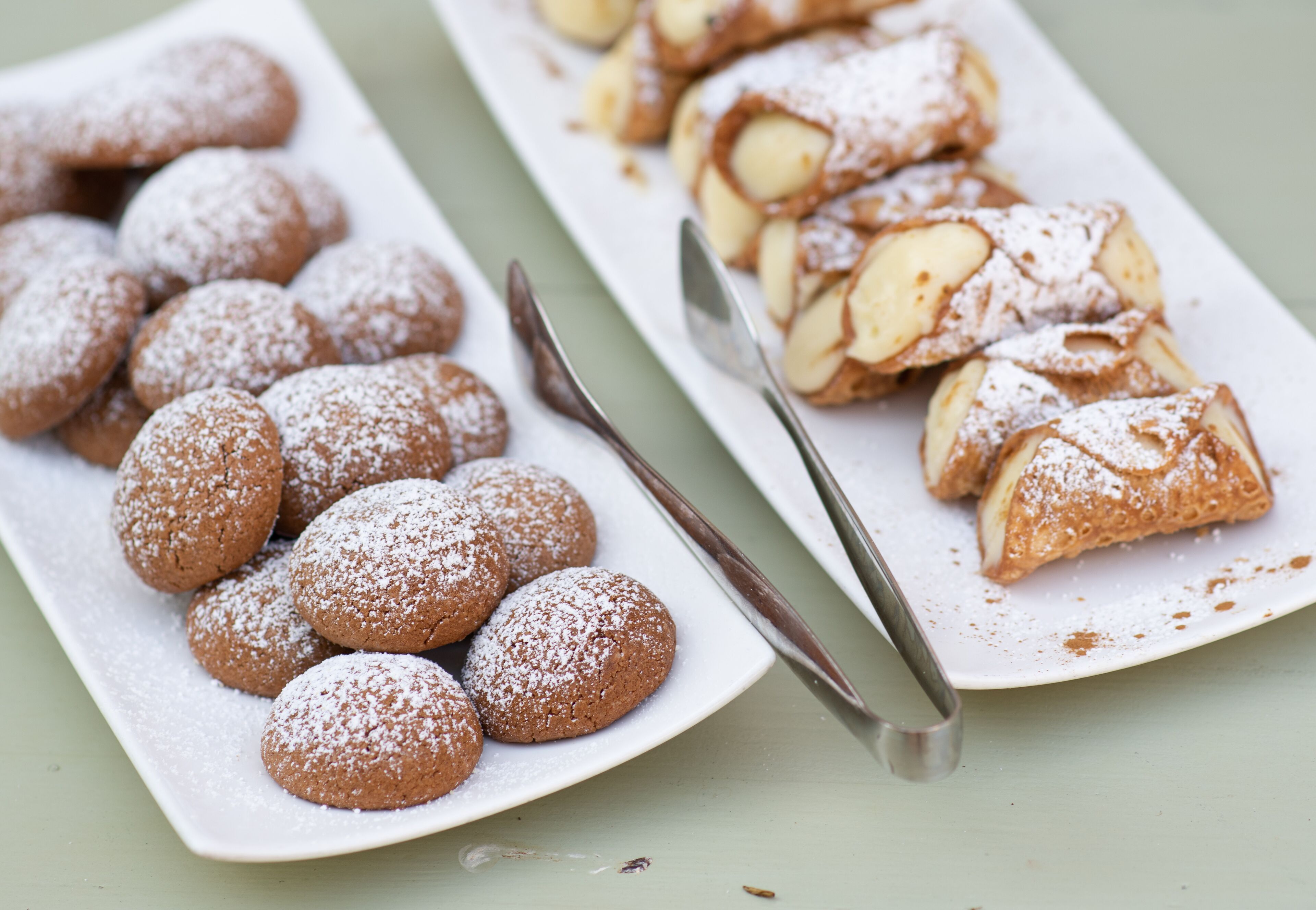 Een bord met suikerbestrooide koekjes en een gebakje met amandelschaafsel.