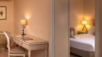 Ein Hotelzimmer mit Schreibtisch, Stuhl, Bett, Nachttisch, Lampe und einem gerahmten Bild an der Wand.