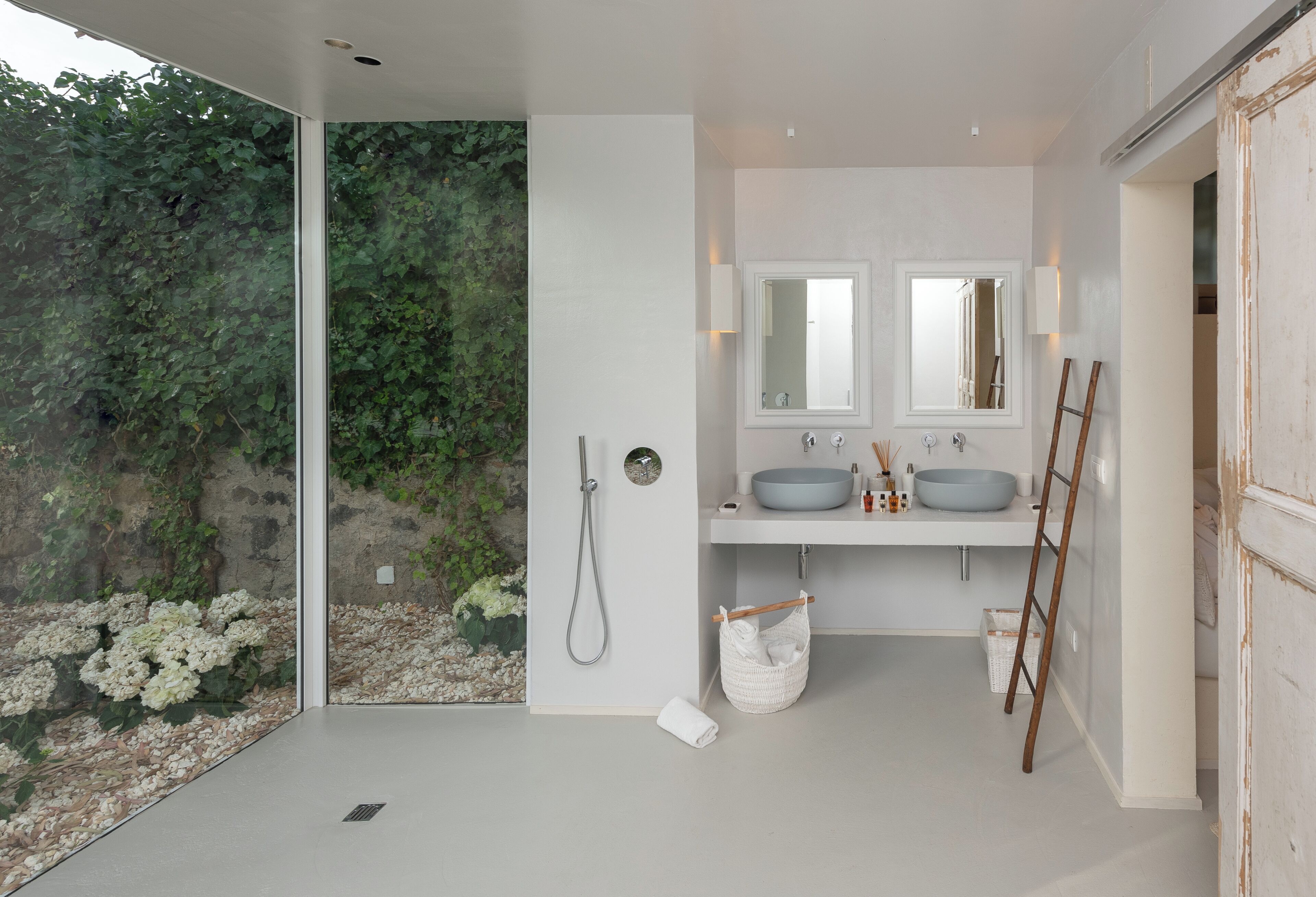 Un baño moderno con un ventanal grande, dos lavamanos, un espejo y una ducha.