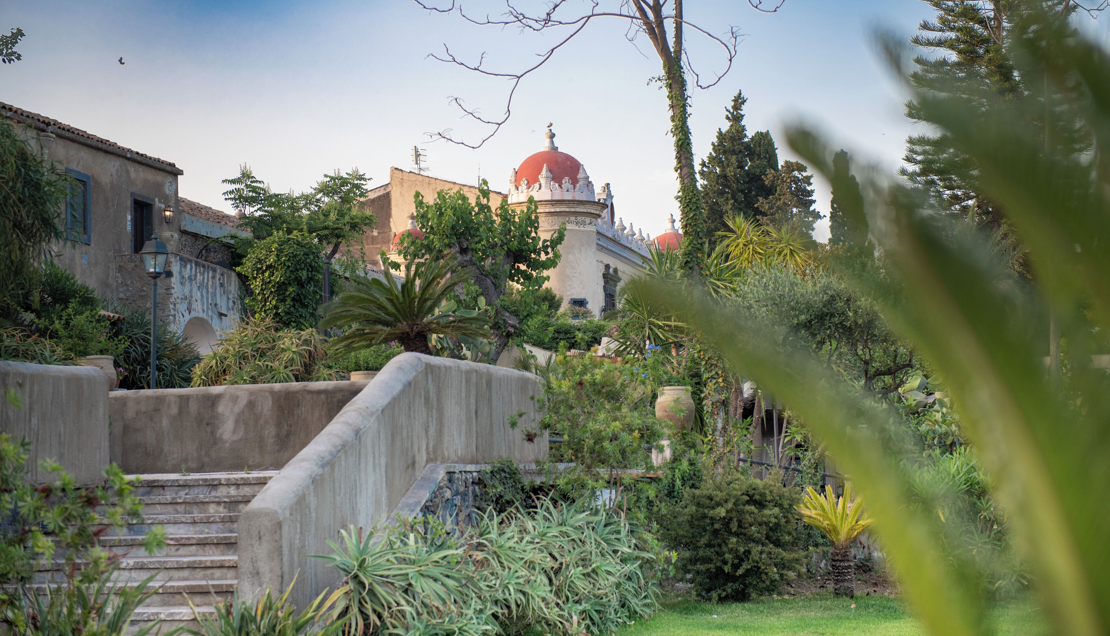 A garden with a stone staircase leading to a building with a red dome.