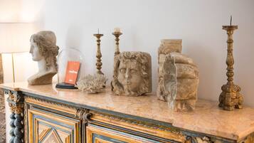 A marble countertop with decorative items including a bust, a glass dome, candles, and a candelabra.