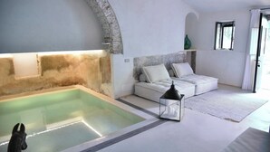 Habitació moderna amb piscina integrada, sofà blanc i finestra petita.