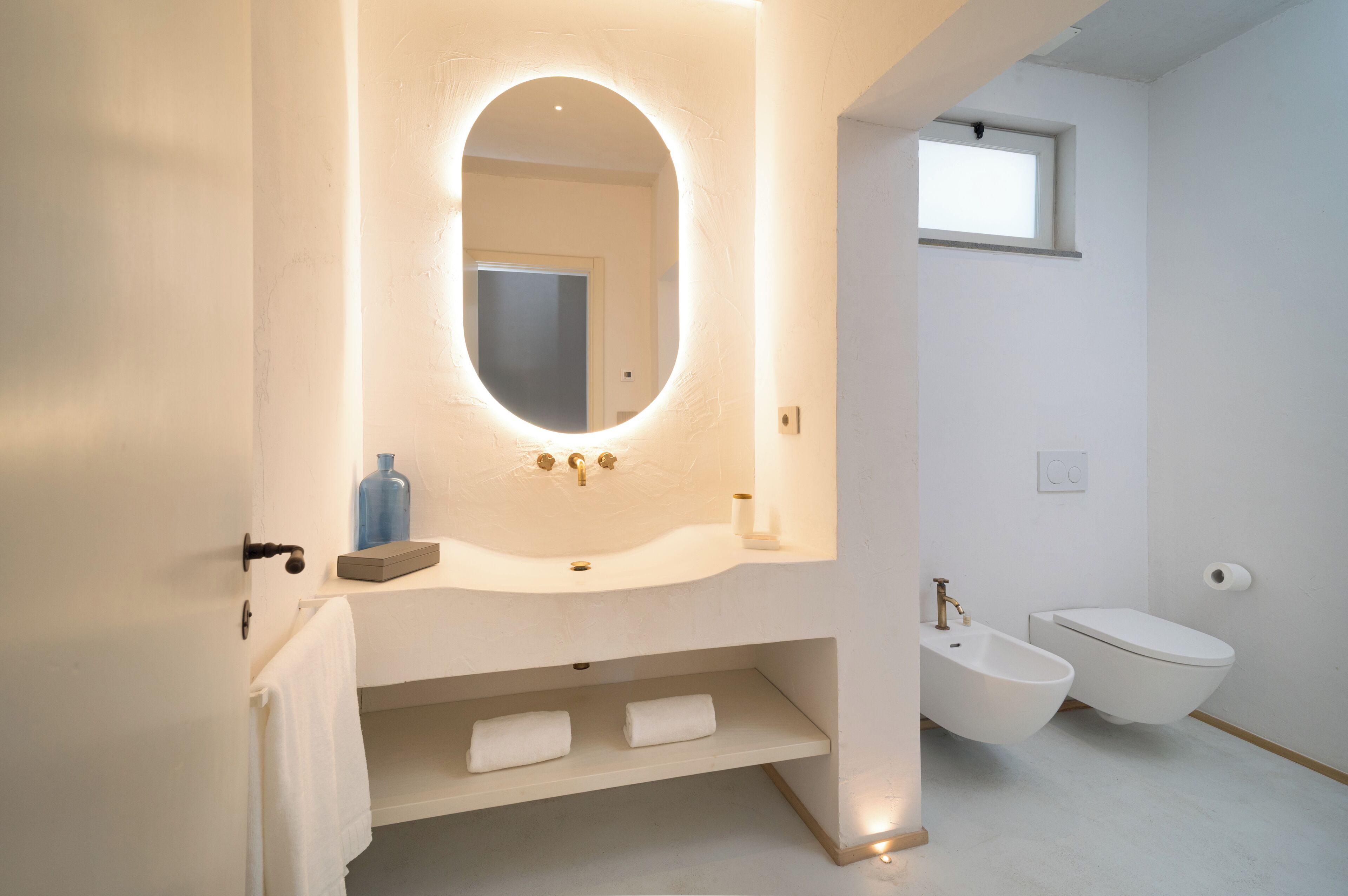 A modern bathroom with a freestanding bathtub, a white sink with a mirror above it, and a toilet.