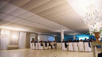 Un salón amplio con techo alto y filas de sillas.