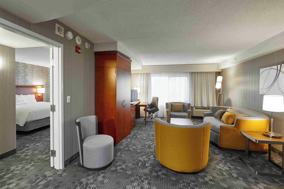 A hotel room with a bed, a desk, a sofa, and a chair.