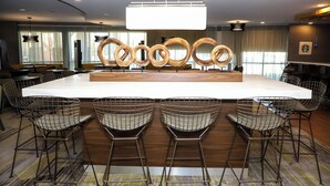 A modern bar area with a central island, bar stools, and pendant lighting. - Courtyard by Marriott Toronto Brampton (Brampton)