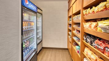 Ein Verkaufsautomatenbereich mit einem Pepsi-Kühlschrank und Regalen voller Snacks wie Sun Chips und Doritos.