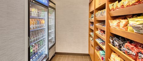 A vending area with a Pepsi refrigerator and shelves stocked with snacks like Sun Chips and Doritos.