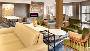 A modern hotel lobby with a stone fireplace, comfortable seating, a flat-screen TV, and large windows. - Fairfield Inn and Suites by Marriott Toronto Brampton (Brampton)