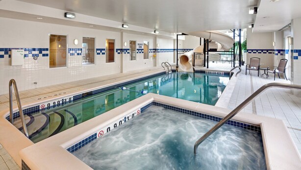 A large indoor swimming pool with a slide, lounge chairs, and a hot tub. - Fairfield Inn and Suites by Marriott Toronto Brampton (Brampton)