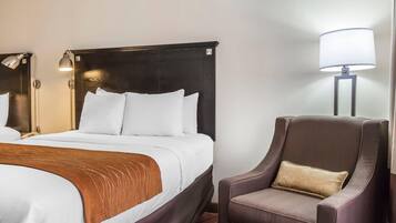 Una habitación de hotel con una cama grande, una silla y dos lámparas de noche.