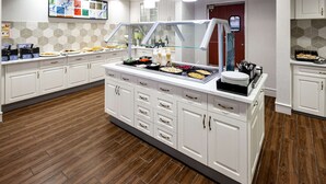 A buffet setup with various food items, a glass display case, and a tiled backsplash. - Homewood Suites by Hilton Jacksonville-South/St. Johns Ctr. (Jacksonville)
