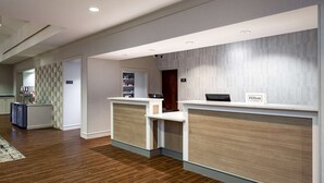 A hotel reception area with two reception desks, a wooden floor, and a modern interior design. - Homewood Suites by Hilton Jacksonville-South/St. Johns Ctr. (Jacksonville)