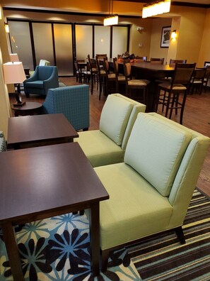 A hotel lobby with a sofa, tables, and chairs.