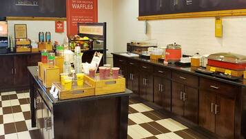 A cafe with a checkered floor, a counter with various food items, and a wall with a chalkboard menu.