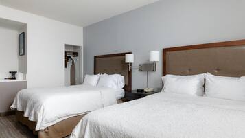 A hotel room with two beds, a bedside table with a lamp, and a small desk with a telephone.