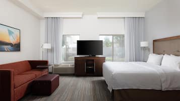 Een hotelkamer met een bed, een bank, een televisie en een schilderij aan de muur.