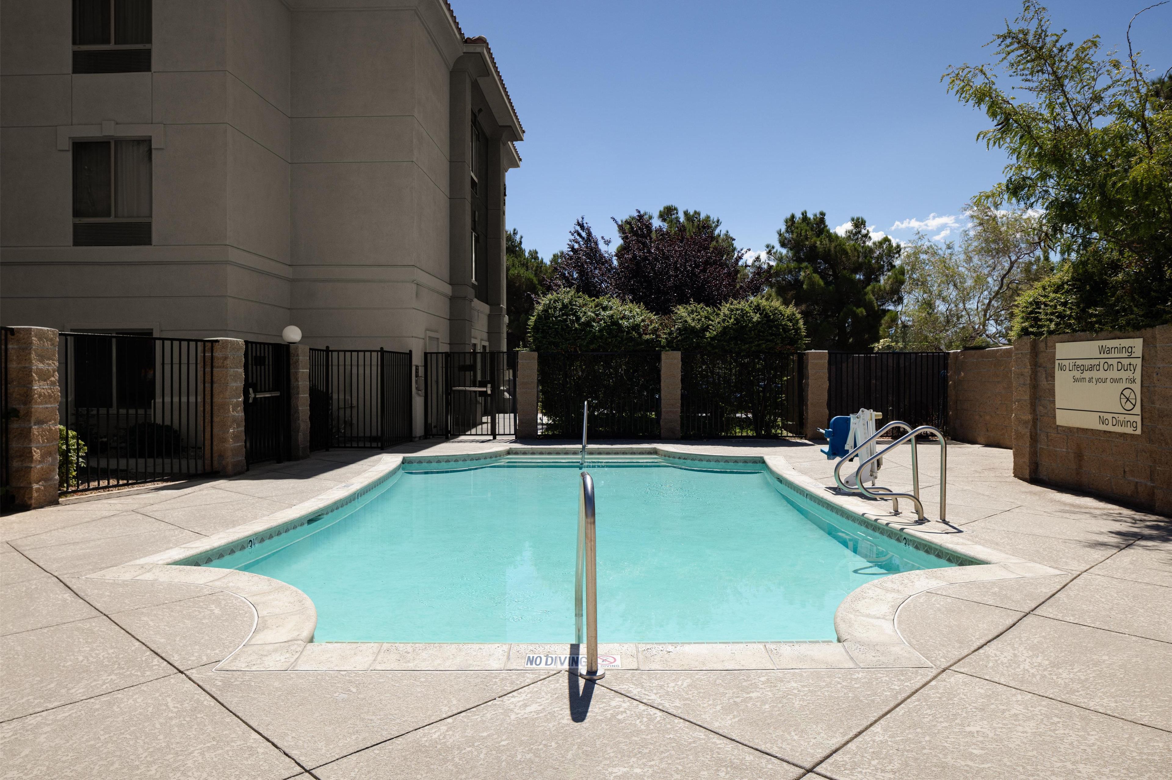 A swimming pool with a no diving sign, surrounded by a building and a fence.