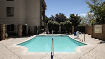 A swimming pool with a no diving sign, surrounded by a building and a fence.
