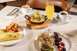 A breakfast setting with a variety of dishes including eggs, potatoes, and berries, along with coffee and juice. - Grand Hyatt DFW - Connected to the airport (Dallas)