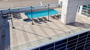 Zona de piscina en la azotea con sillones de descanso y vistas al aeropuerto.