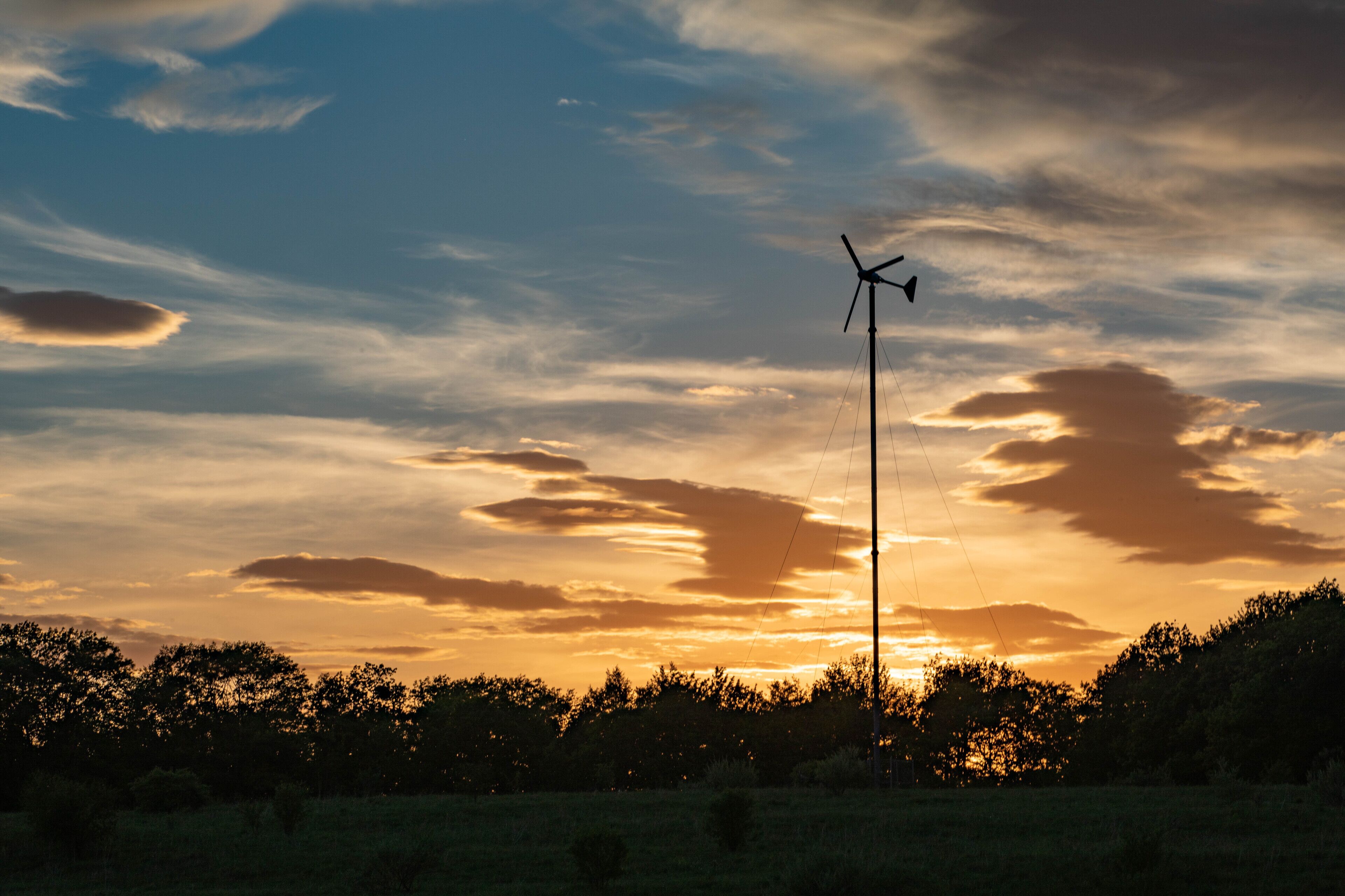 Een windturbine in een veld met een ondergaande zon.