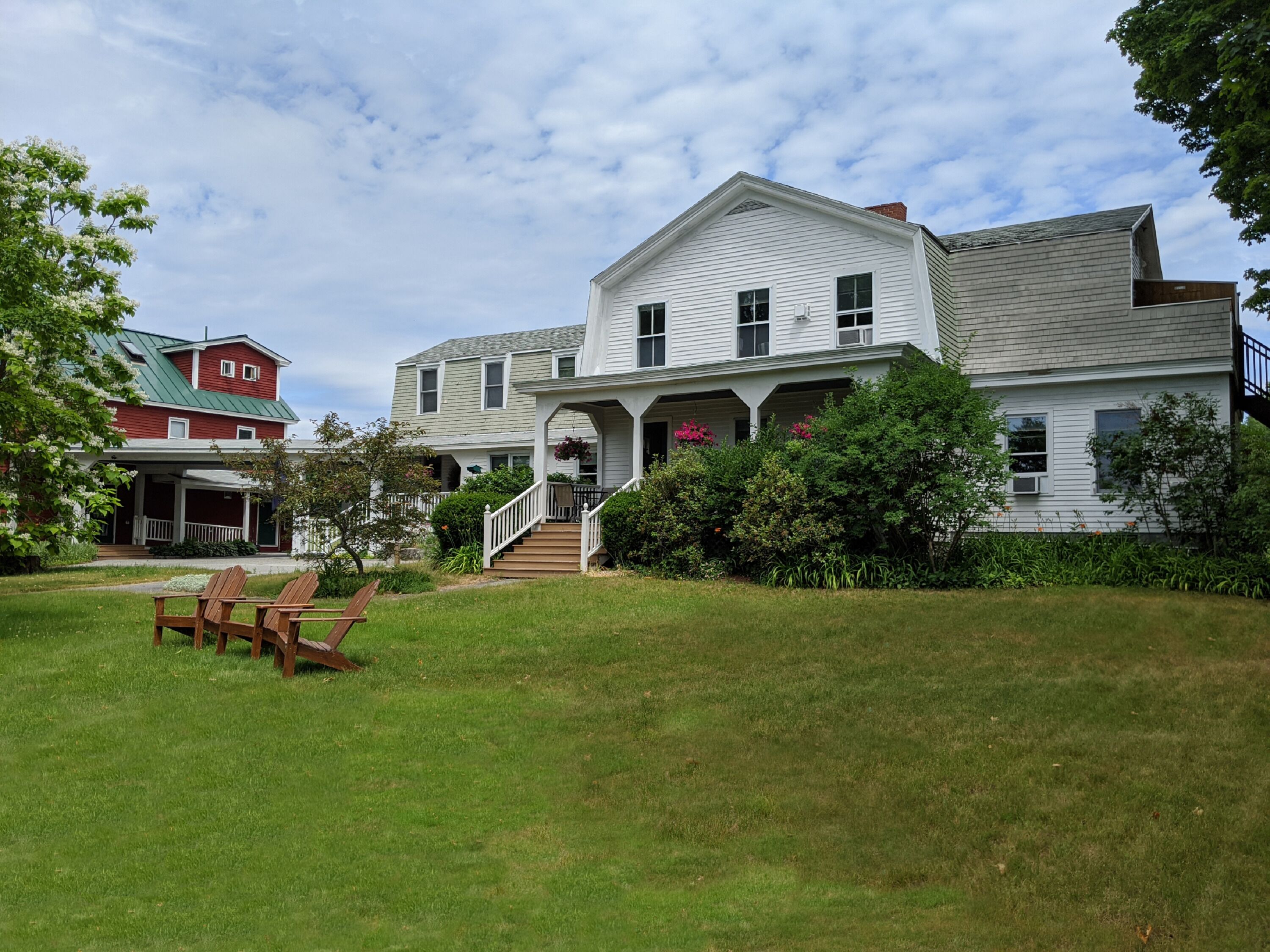 A large white house with a porch and a staircase leading to the entrance.