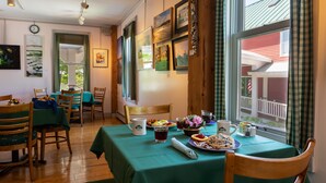 A dining area with a table set for two, featuring a green tablecloth, plates of food, and a coffee mug. - Maple Hill Farm Inn (Hallowell)