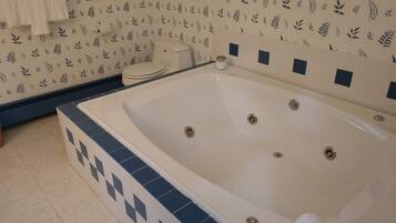 A bathroom with a large bathtub, a toilet, and a sink.