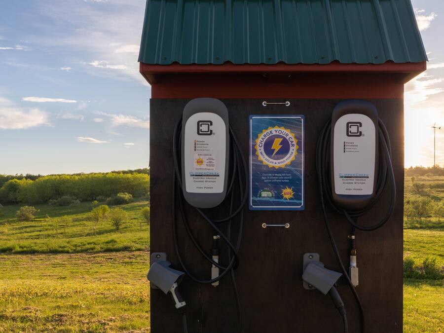 Een laadstation voor elektrische voertuigen, aangedreven door zonne-energie, met twee oplaadpunten, gelegen in een landelijke omgeving.