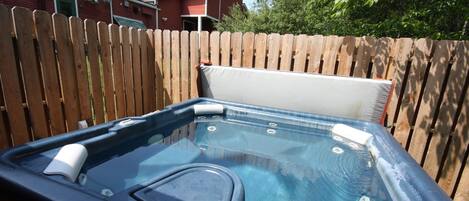 Un jacuzzi con un cerco de madera y una casa al fondo.