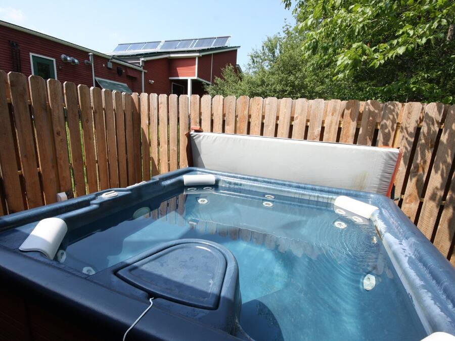 A hot tub with a wooden fence and a house in the background.
