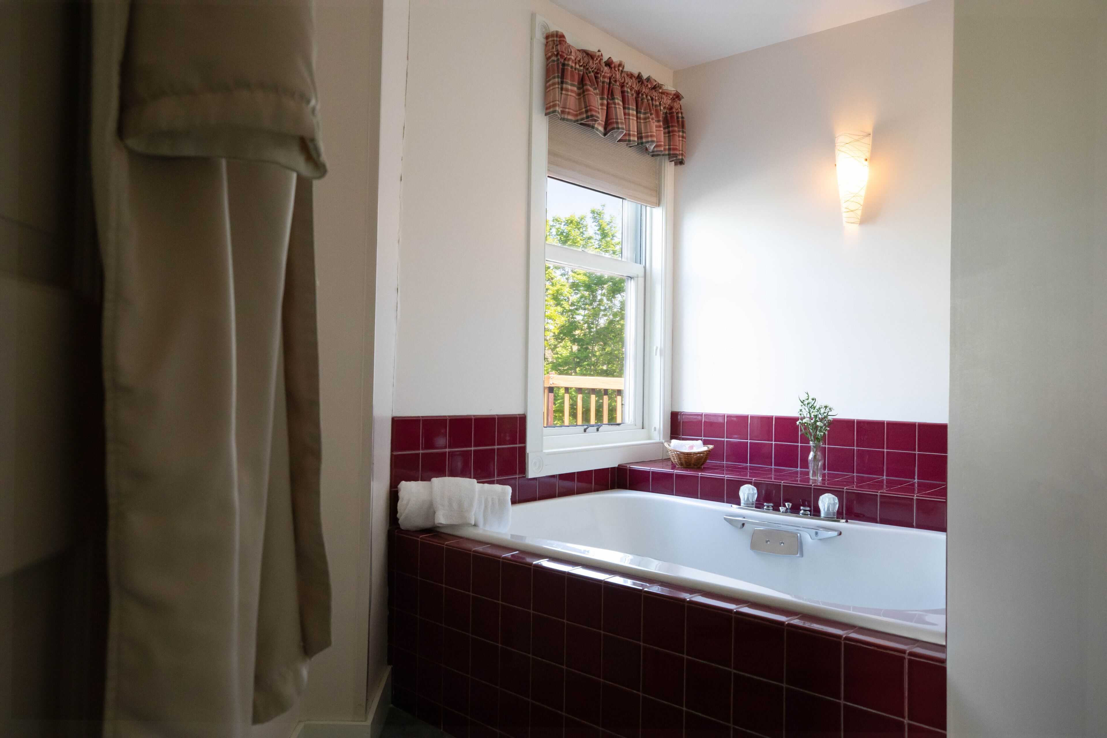 A bathroom with a bathtub, a window with a view, and a towel rack.