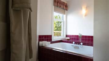 A bathroom with a bathtub, a window with a view, and a towel rack.