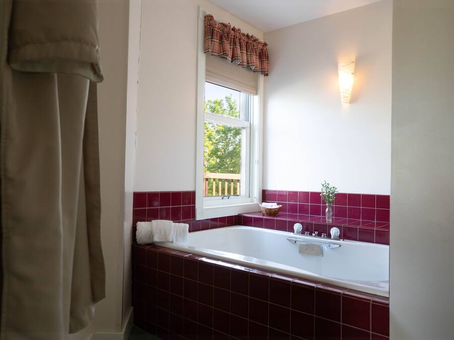 A bathroom with a bathtub, a window with a view, and a towel rack.