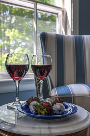 A table with two wine glasses and a plate of strawberries.