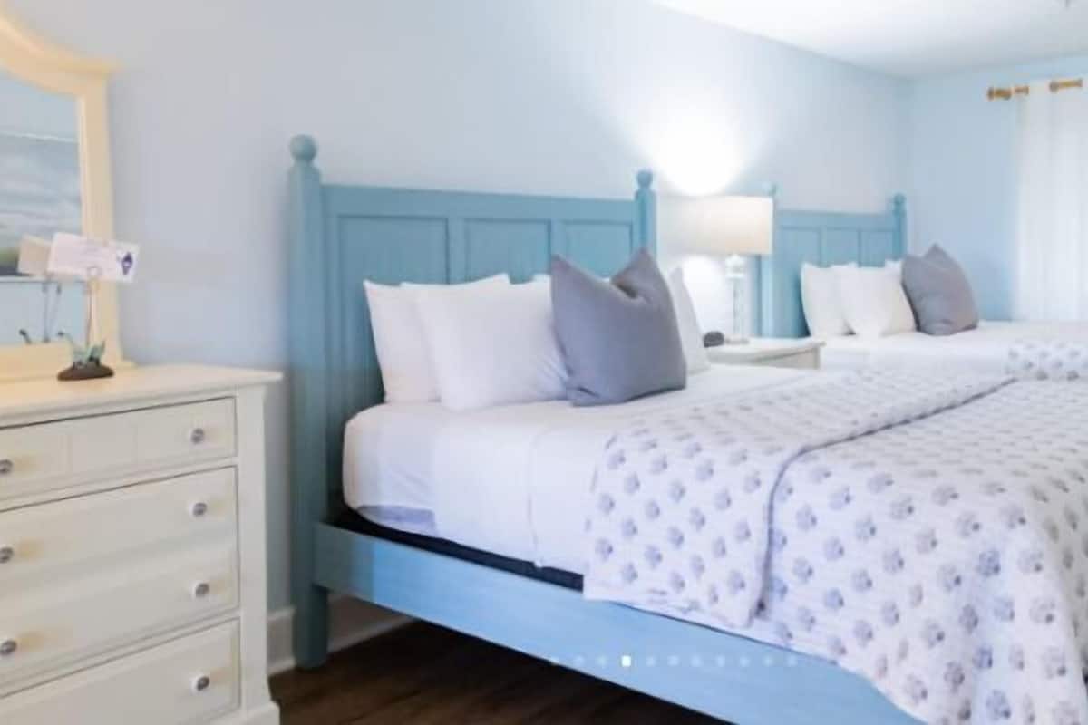 A bedroom with a bed, bedside tables, a dresser, and a window with curtains.