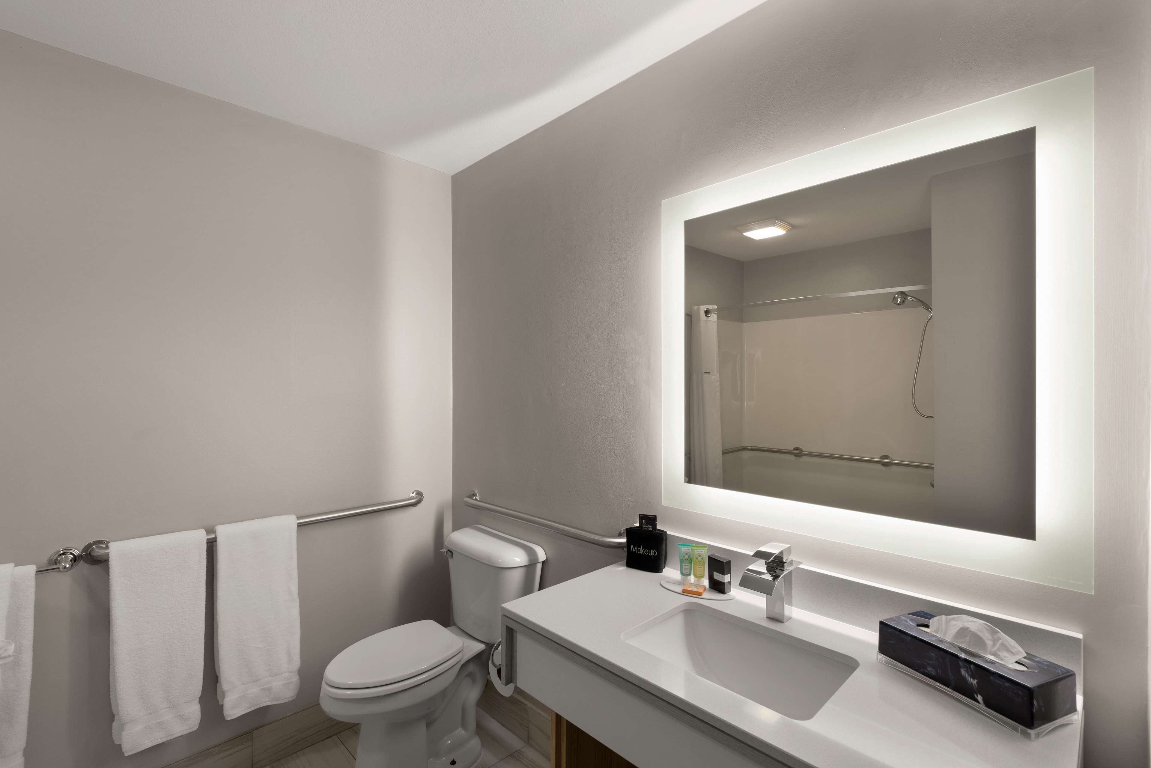 A modern bathroom with a white sink, mirror, and toilet.