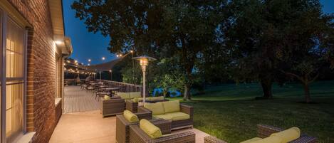 Un espace extérieur aménagé en terrasse, avec des meubles en osier et des guirlandes lumineuses.