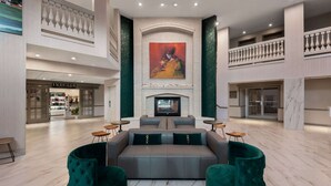 Un hall d’entrée spacieux avec un espace salon central, une cheminée et une grande œuvre d’art au-dessus.