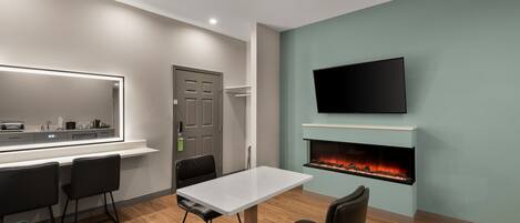 A modern room with a dining table, chairs, a flat-screen TV, and a fireplace.