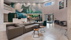 Un vestíbulo amplio con diseño moderno, que incluye un gran sofá modular, una zona de bar y un área de estar con sillas y mesas.