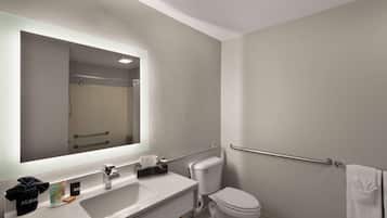 A modern bathroom with a large mirror, white sink, and toilet.