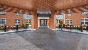 Un pasaje cubierto que conduce a la entrada de un edificio con paredes de ladrillo y techo de madera.